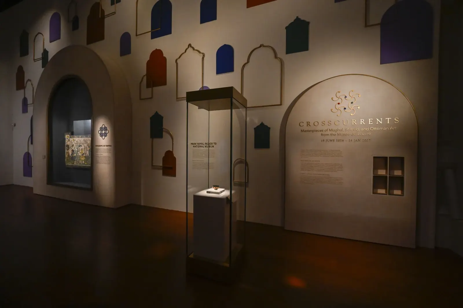 The exhibition entrance wall: scattered arches in jewel tones and gold outline